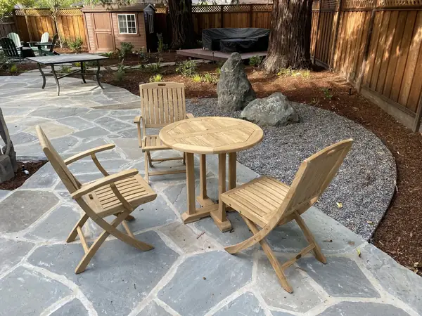 Flagstone patio with a teak bistro table and boulders